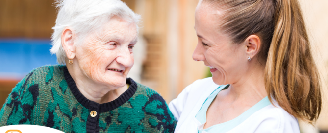 A professional caregiver compassionately hugs a senior client.
