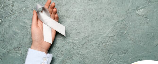 A woman holds a silver ribbon, representing Parkinson’s Awareness Month.